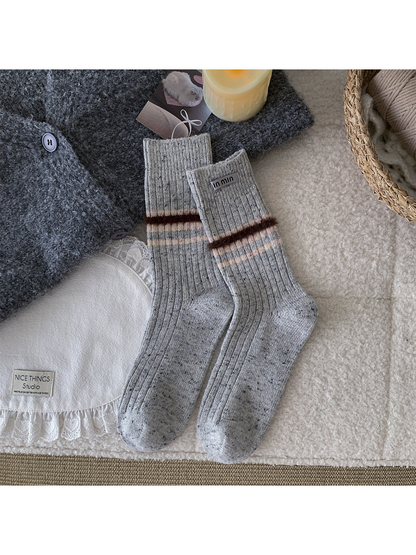 Light gray crew socks with a fuzzy brown band and narrow pastel stripes