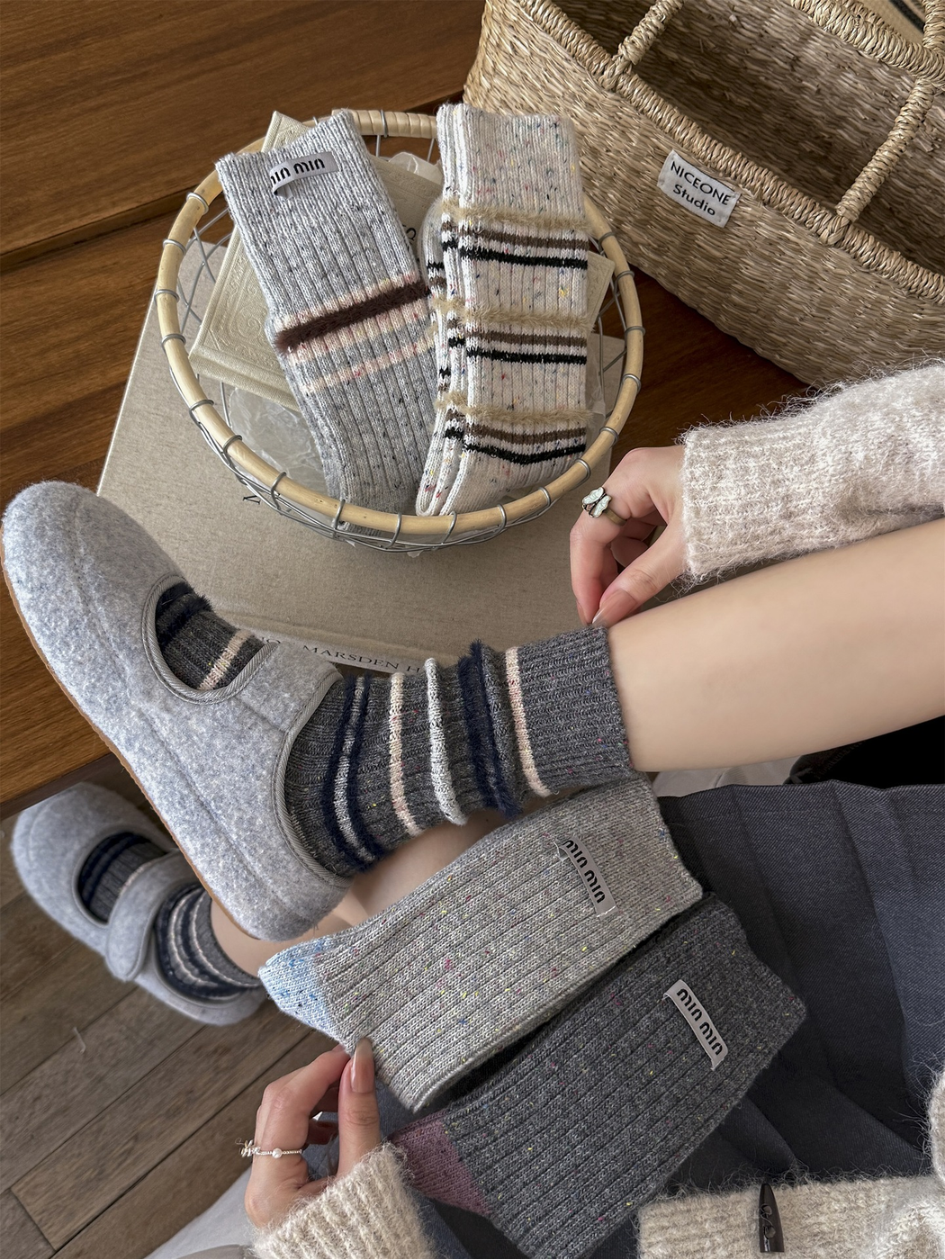 Dark gray striped crew socks worn with gray felt slippers in a styled indoor setting