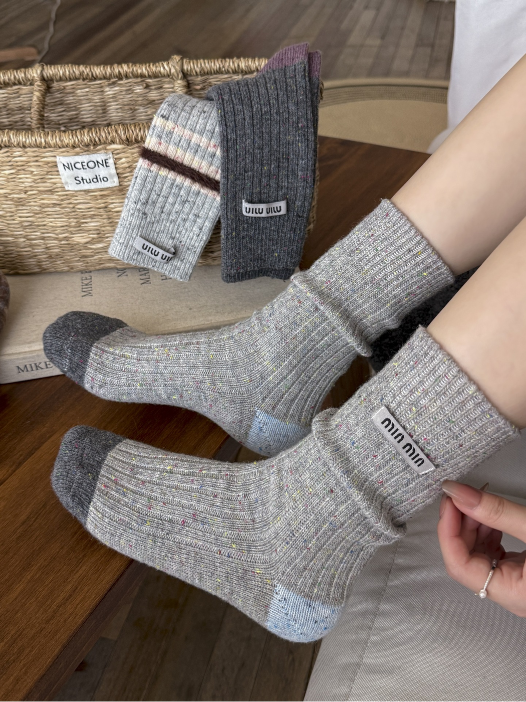 Gray speckled crew socks with contrasting blue and dark gray toes worn indoors