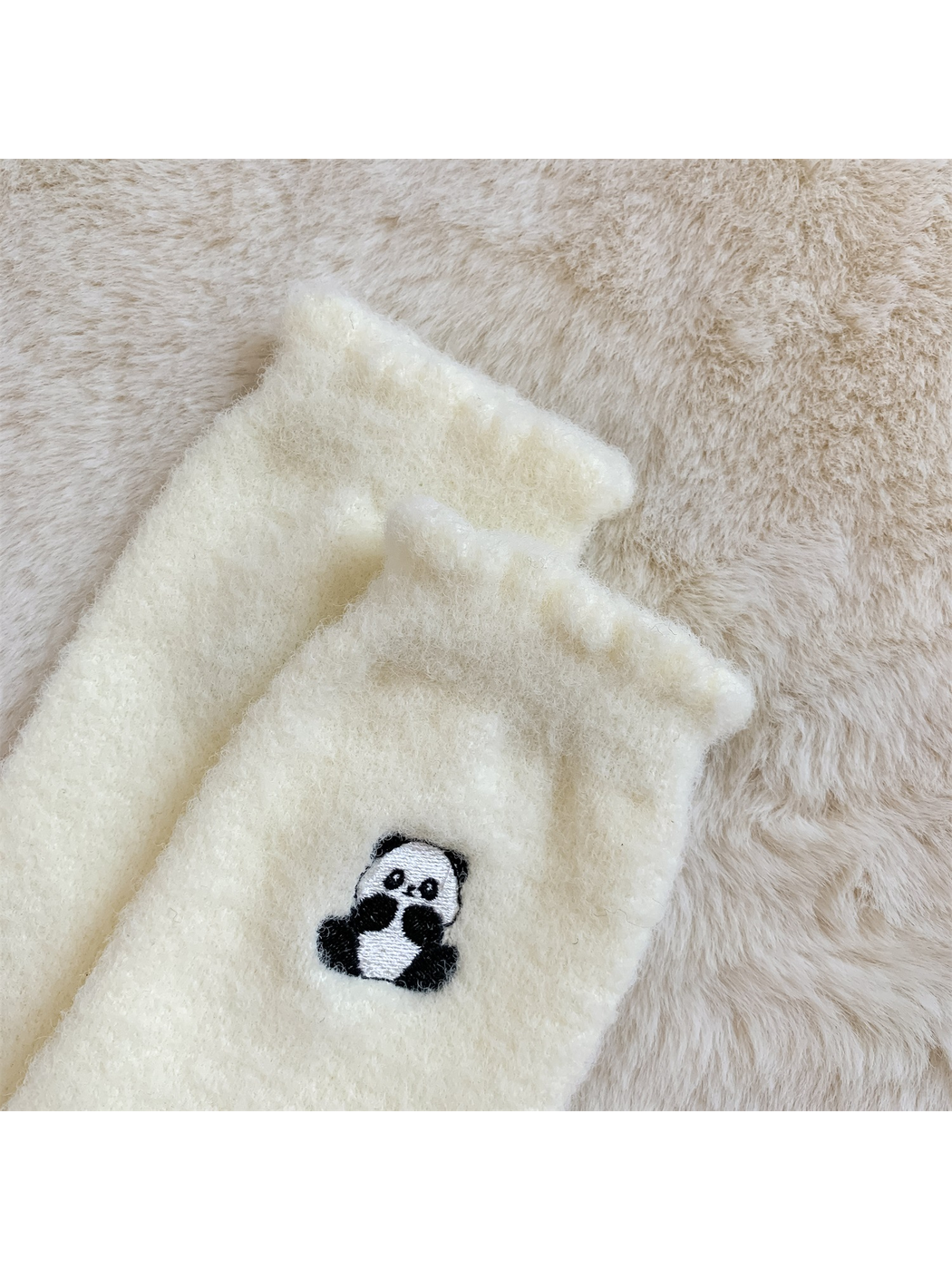 Close-up of the ivory sock cuff and embroidered seated panda motif