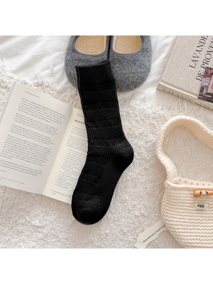 Black crew sock with alternating ribbed bands and diamond-knit motifs