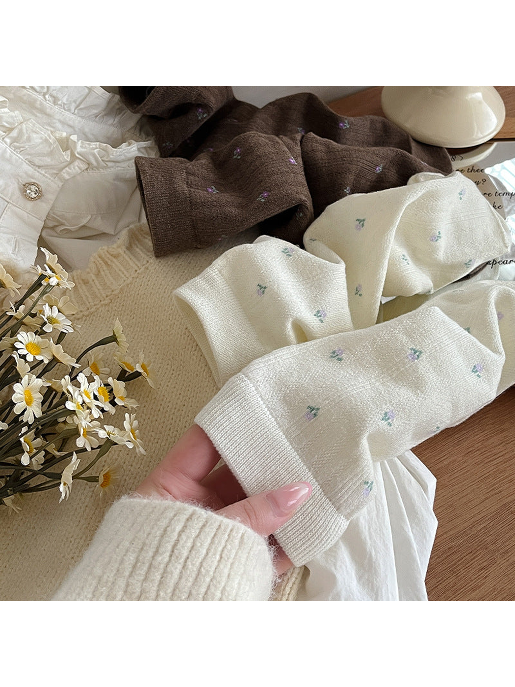 Ivory and brown floral crew socks arranged with knit accessories