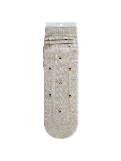 Beige crew sock with tiny dark floral motifs and a ribbed cuff