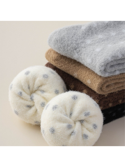 Close-up of folded fuzzy polka-dot socks in cream, gray, camel, brown and black