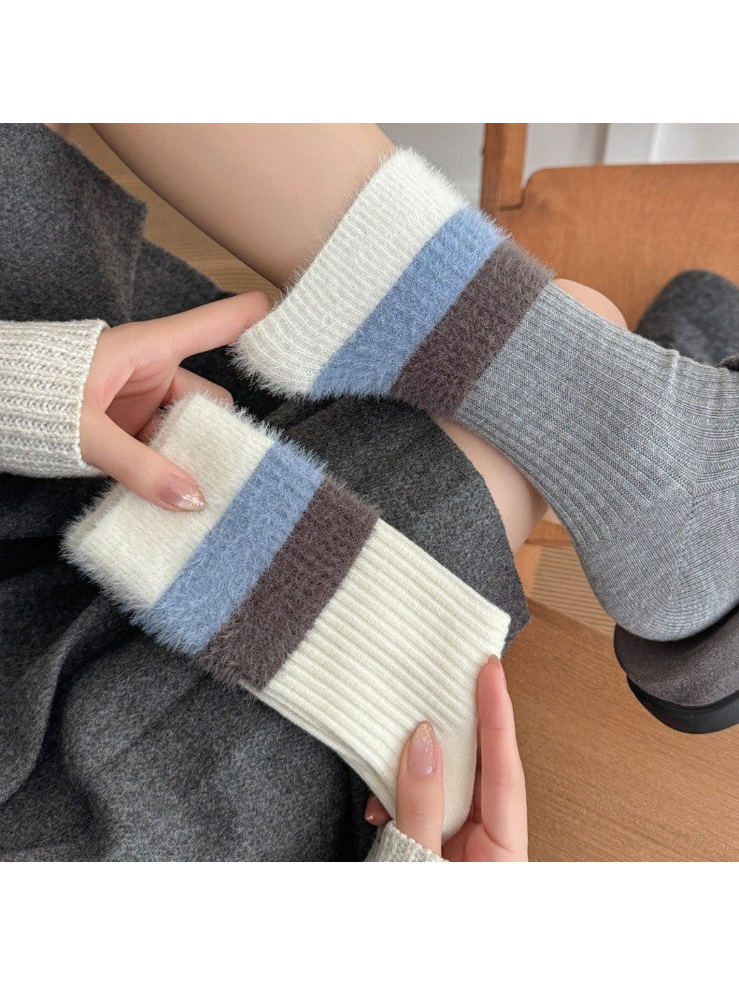 Cream and light gray ribbed crew socks displayed in a seated lifestyle setting