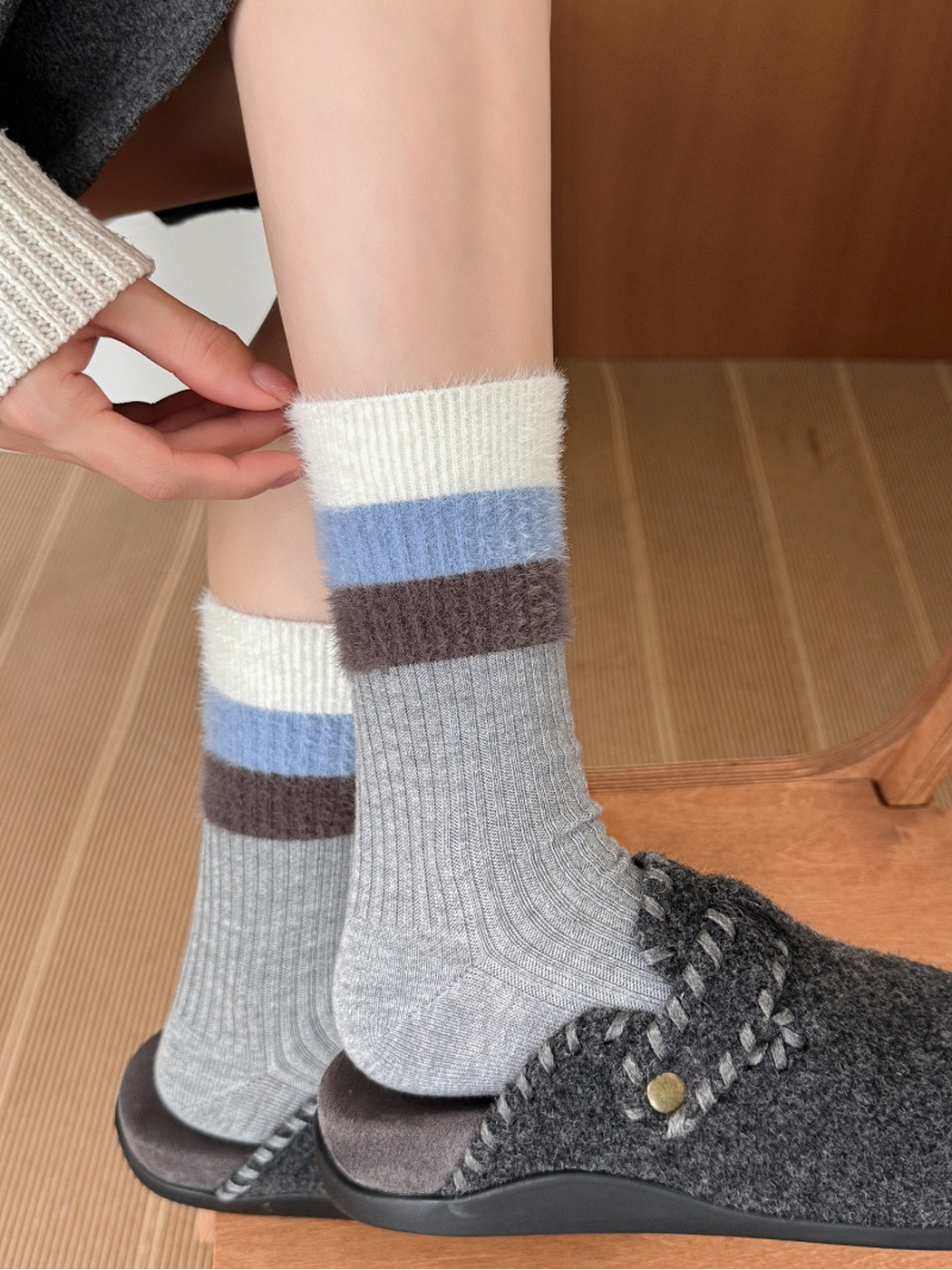 Light gray ribbed crew socks with fuzzy striped cuffs worn with gray clogs