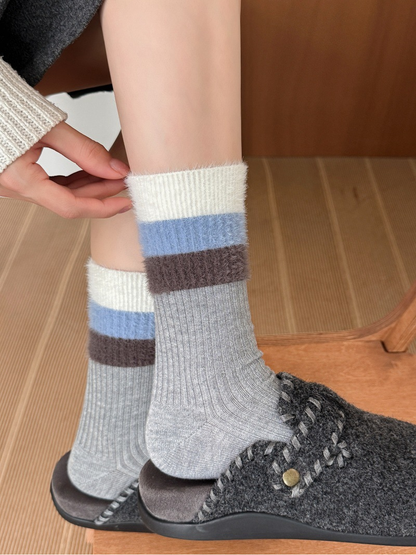 Light gray ribbed crew socks with fuzzy striped cuffs worn with gray clogs