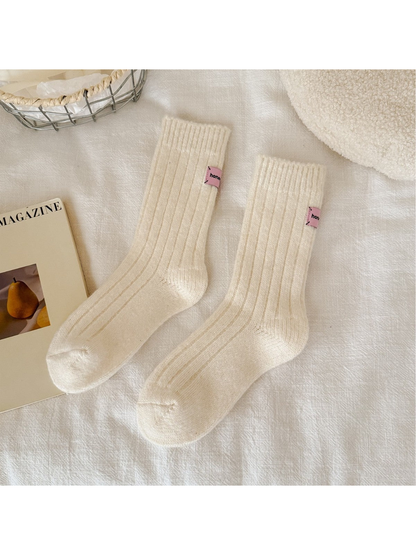 Cream ribbed crew socks with pink cuff patches, full pair view