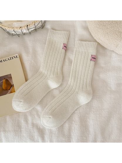 White ribbed crew socks with pink cuff patches, full pair view