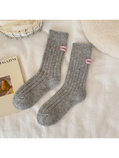 Light gray ribbed crew socks with pink cuff patches, full pair view
