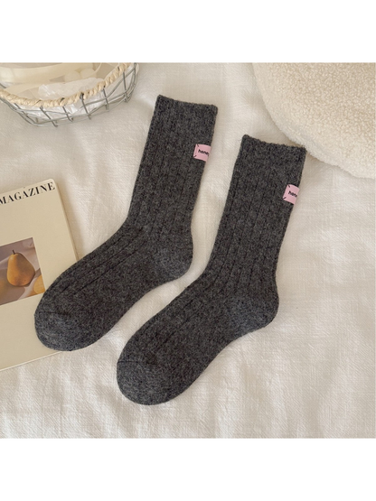 Dark gray ribbed crew socks with pink cuff patches, full pair view
