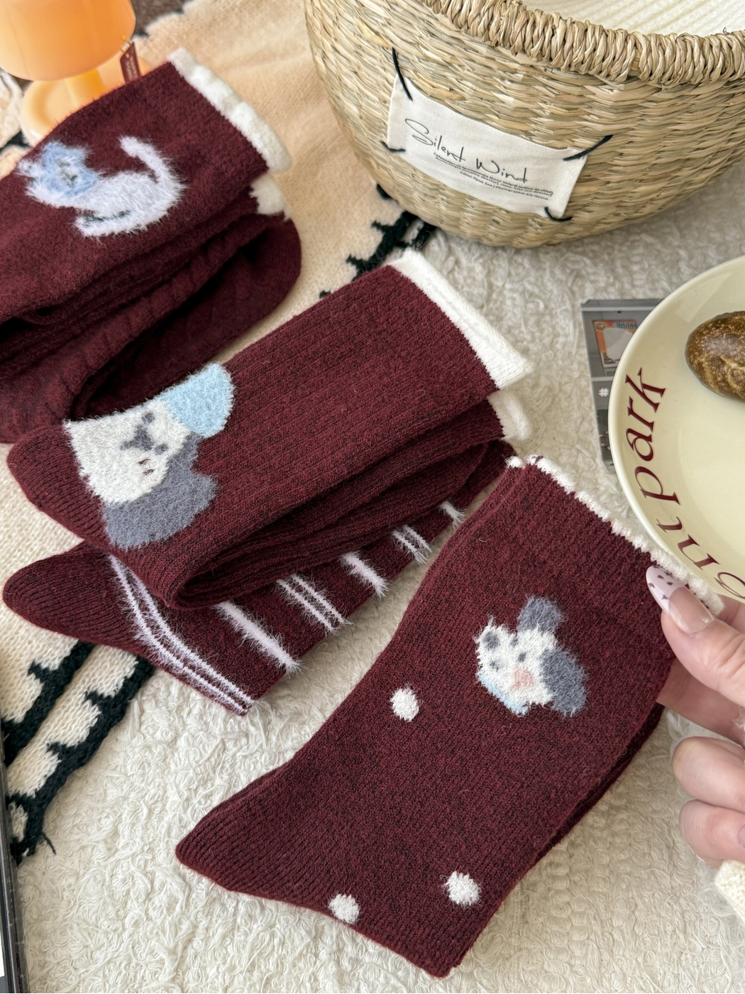 Close display of burgundy crew socks with striped and fuzzy animal motifs