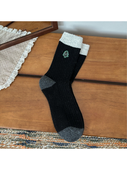 Black ribbed crew socks with light cuffs, gray trim and Christmas tree embroidery