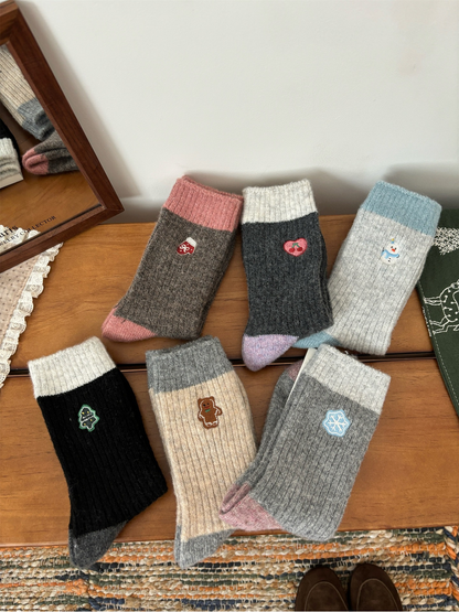 Six embroidered ribbed crew sock styles arranged on a wooden tabletop