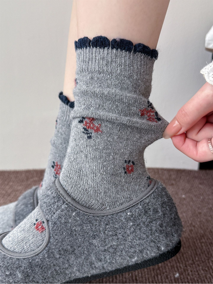 Close-up of the gray floral socks with dark scalloped cuff edging