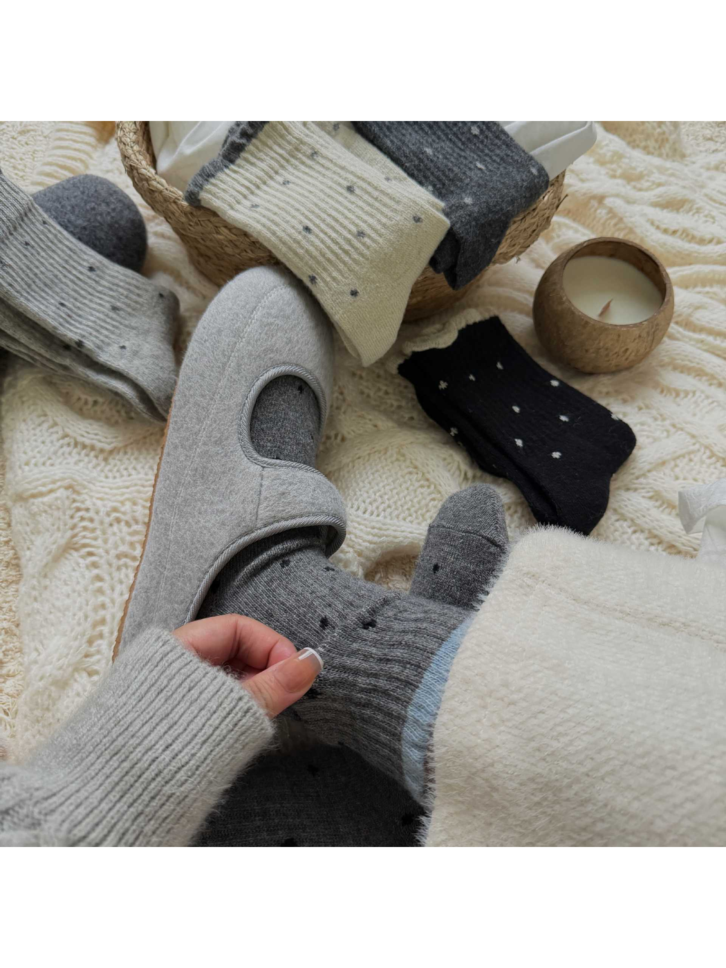 Gray polka-dot socks styled with gray slippers in a cozy setting