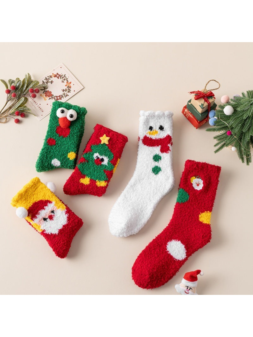 Five fuzzy Christmas character socks displayed with holiday decorations