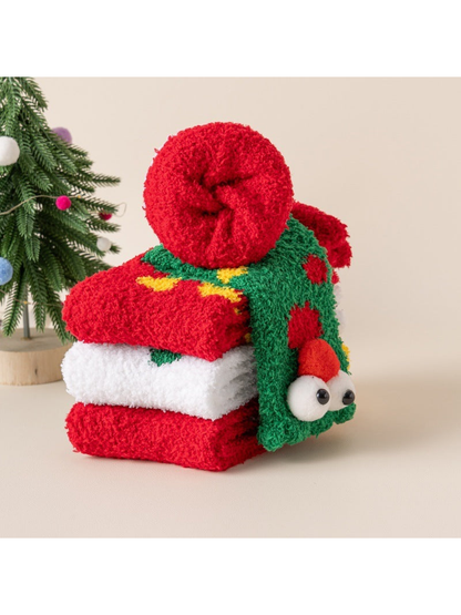 Fuzzy Christmas socks folded, stacked and rolled beside a decorated tree