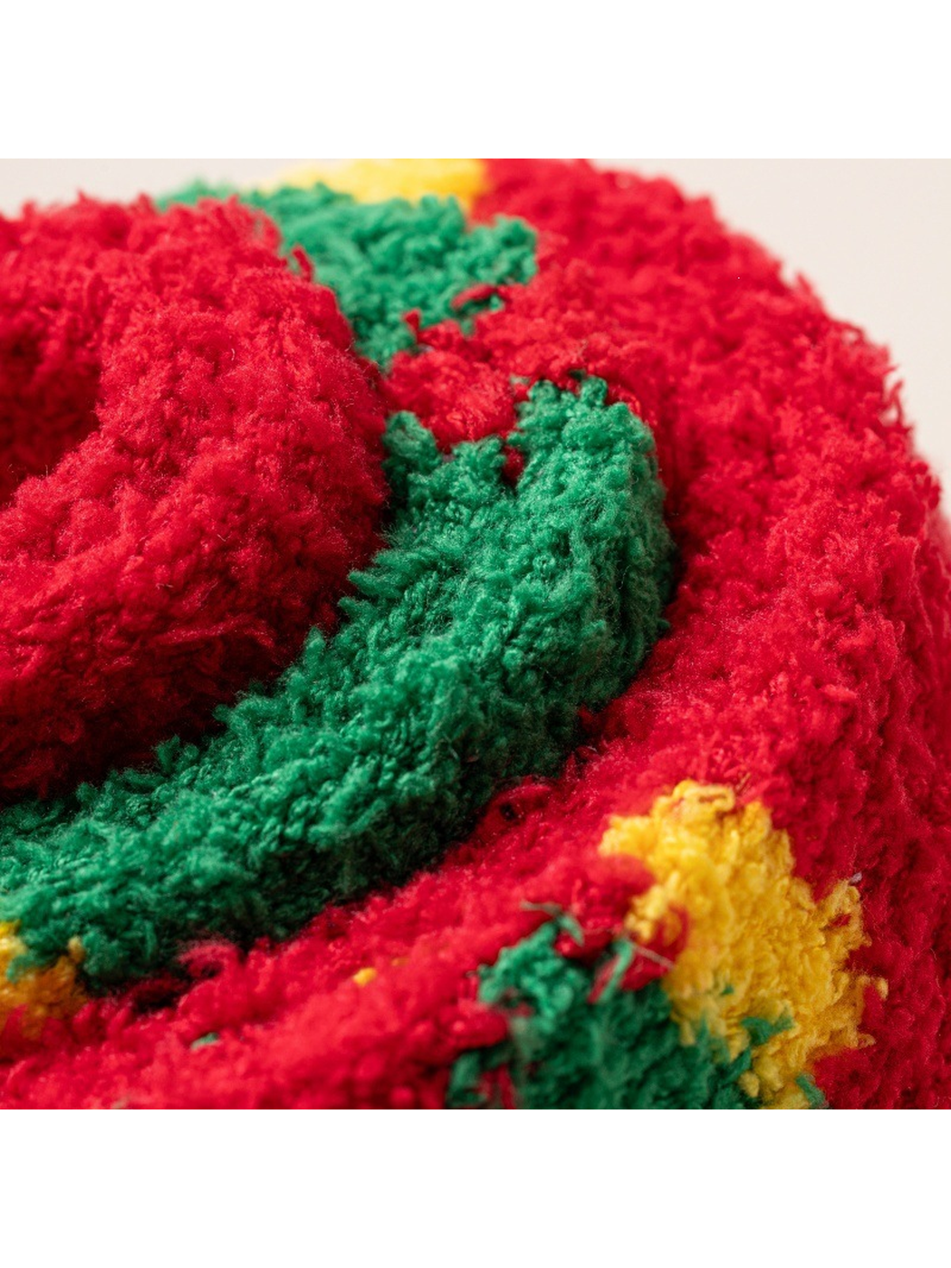Close-up of rolled fuzzy socks with layered red, green and yellow motifs