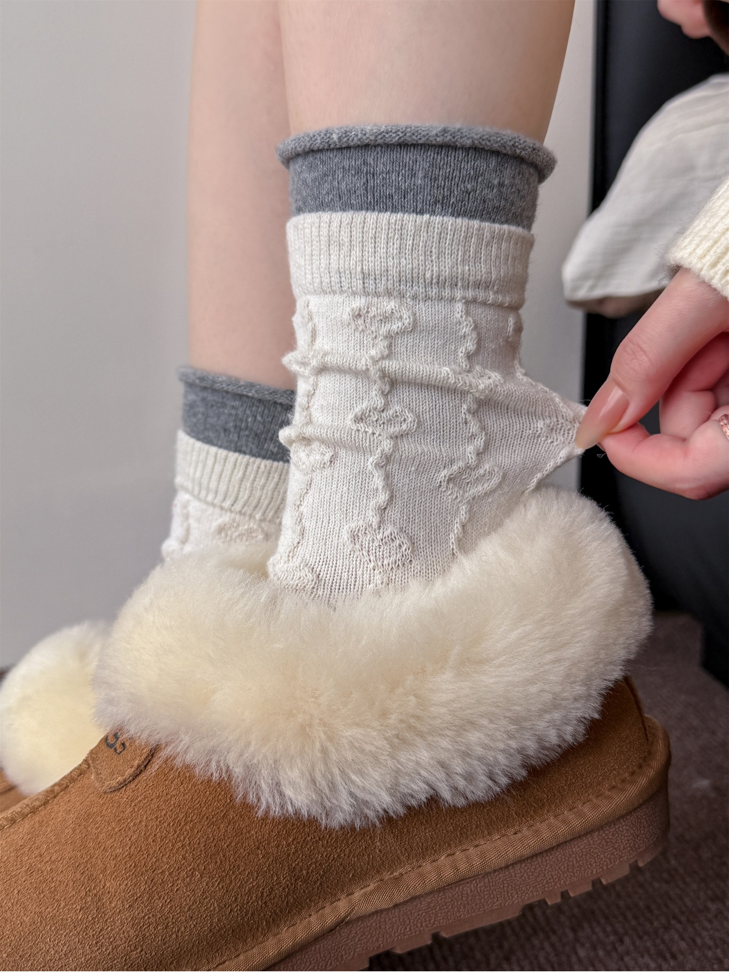 Close-up of an ivory textured crew sock being gently stretched at the ankle