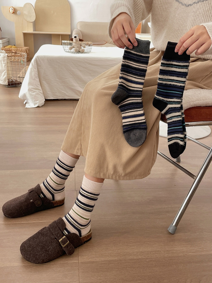 Ivory striped socks worn while gray and black striped styles are held for comparison