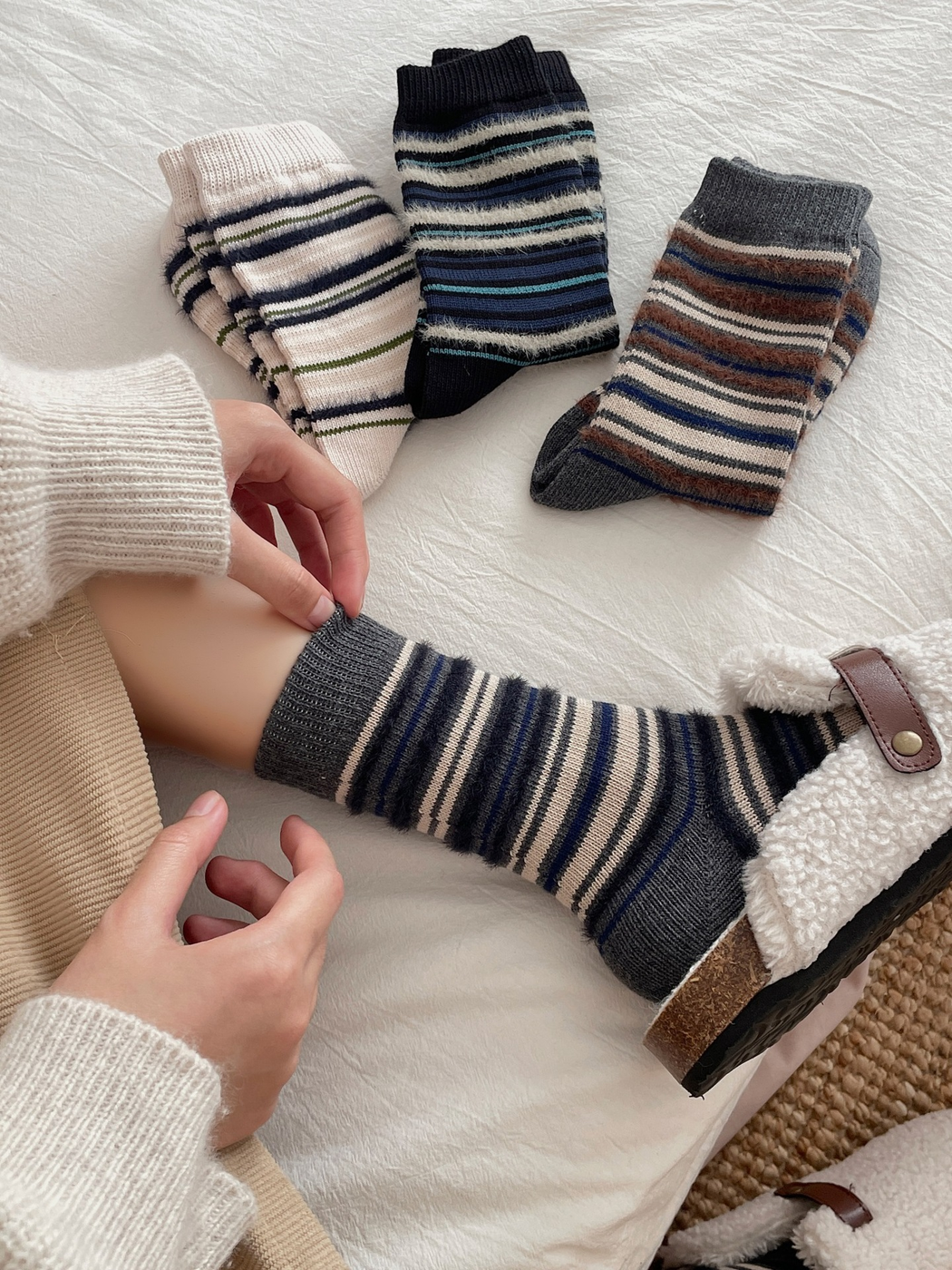 Gray striped crew socks worn beside three folded color styles