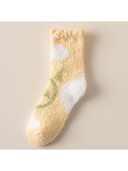 Yellow fuzzy crew sock with pink flower, green stem, and white patches