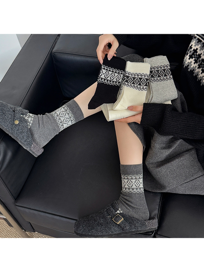 Dark gray geometric crew socks worn with clogs while three color options are held together