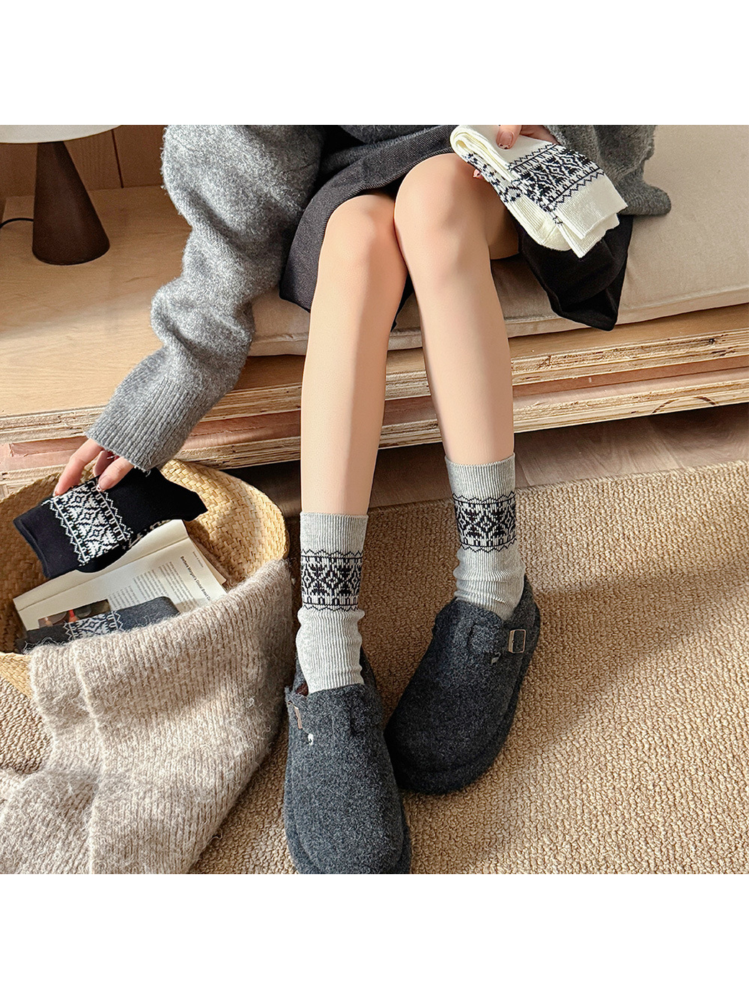 Light gray geometric crew socks worn with dark gray clogs in a neutral indoor setting