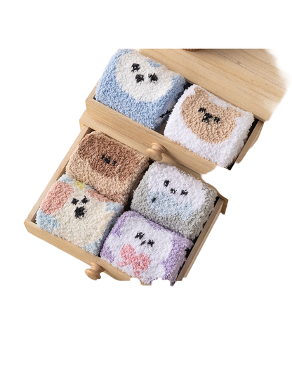 Assorted fuzzy animal-motif crew socks arranged in wooden drawers