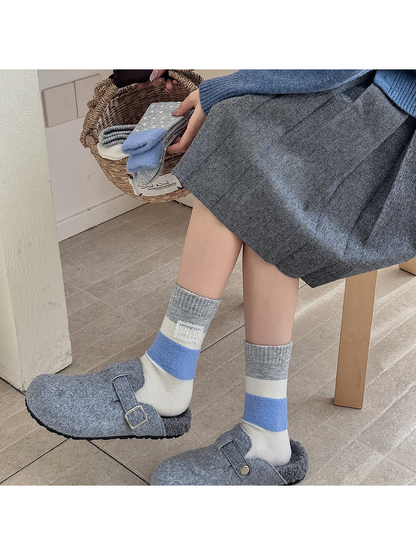 Gray, cream and blue color-block crew socks worn with gray clogs