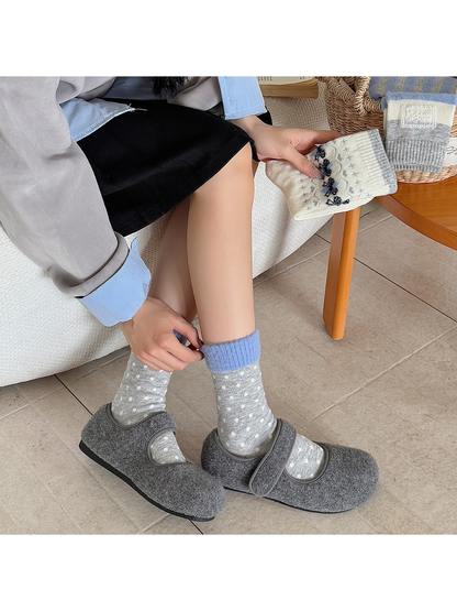 Gray polka-dot crew socks with blue fuzzy cuffs worn with gray clogs