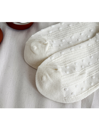 Close-up of the ivory socks' rounded toes and dotted knit panels