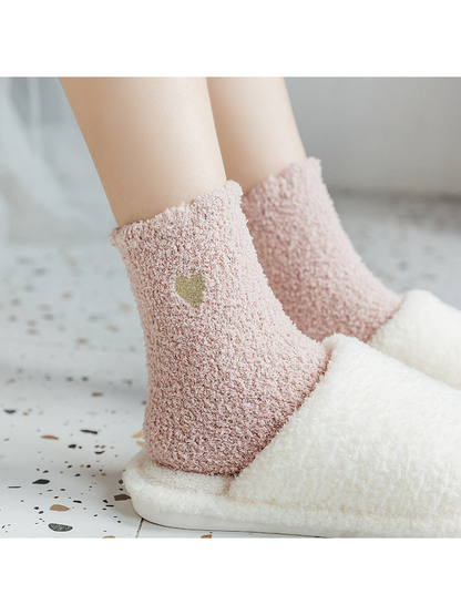 Pink fuzzy heart-detail socks worn with plush slippers