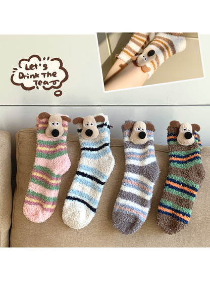Four striped fuzzy dog socks displayed together on a sofa