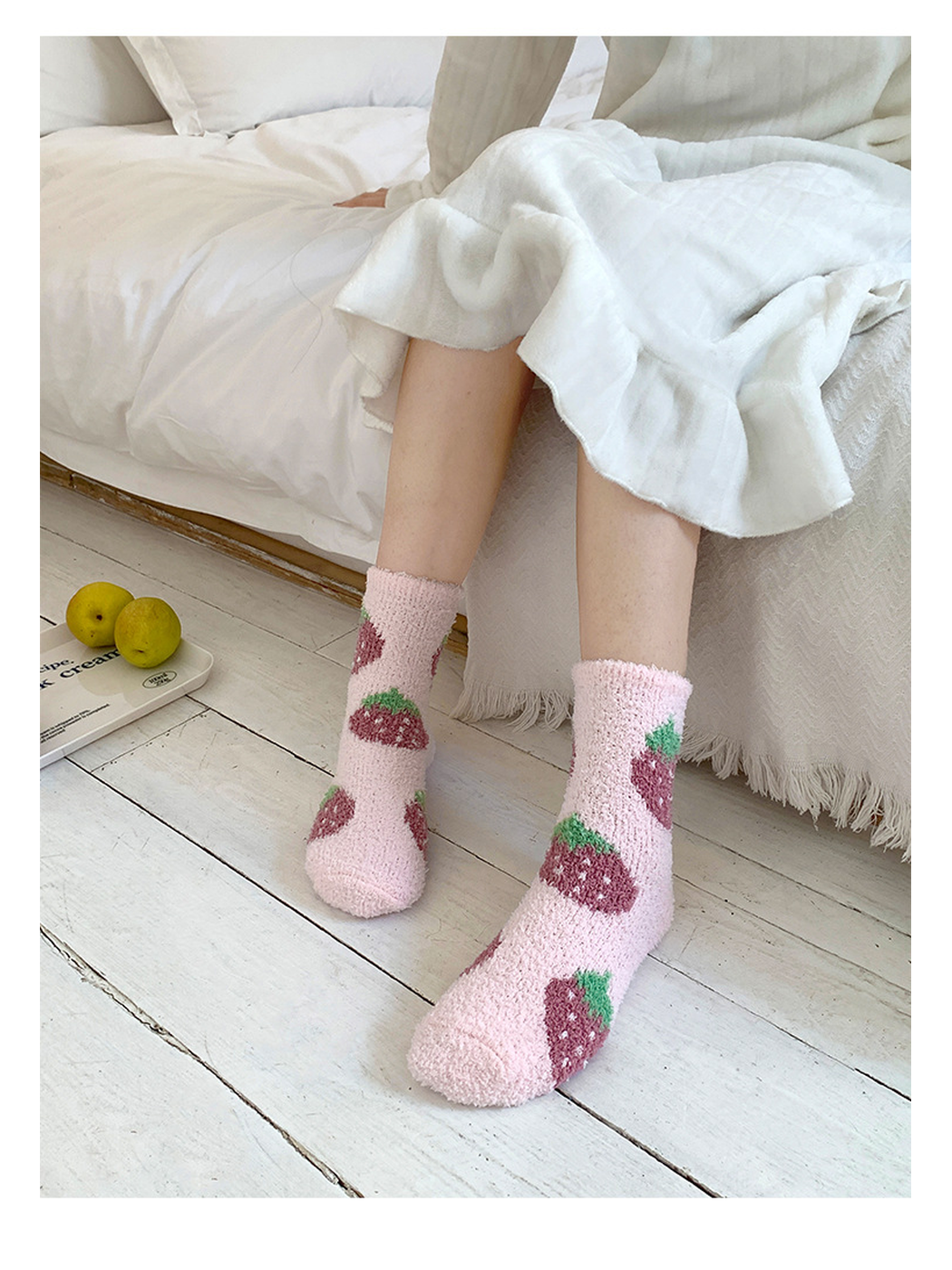 Pink strawberry-pattern fuzzy crew socks worn beside a bed