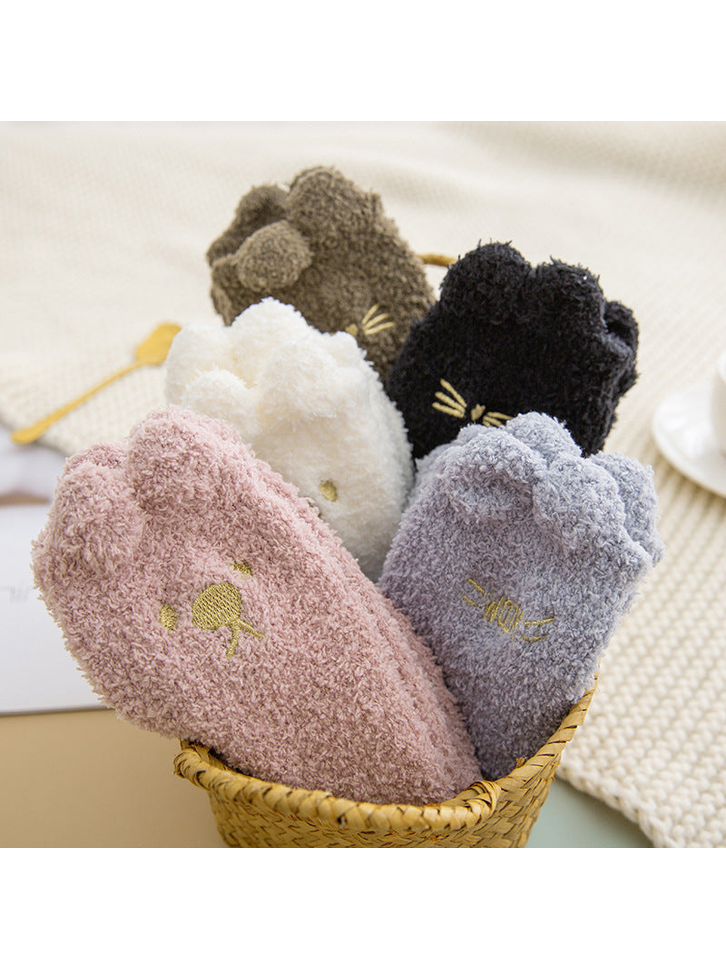 Assorted fuzzy cat socks displayed upright in a woven basket