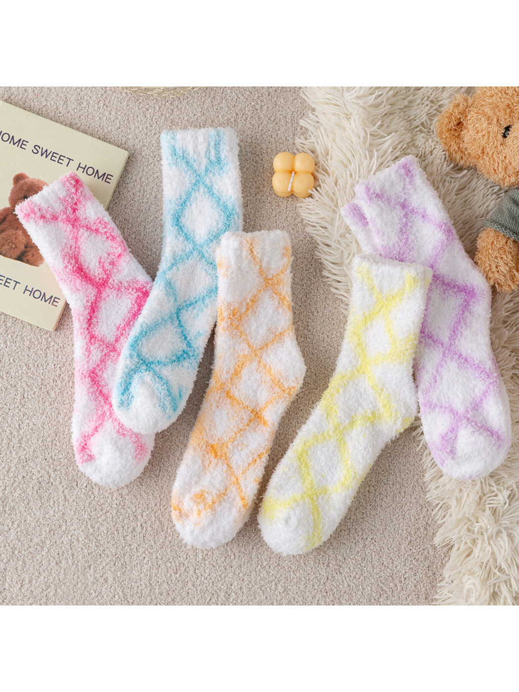 Five fuzzy white crew socks with colorful diamond patterns in a styled flat lay