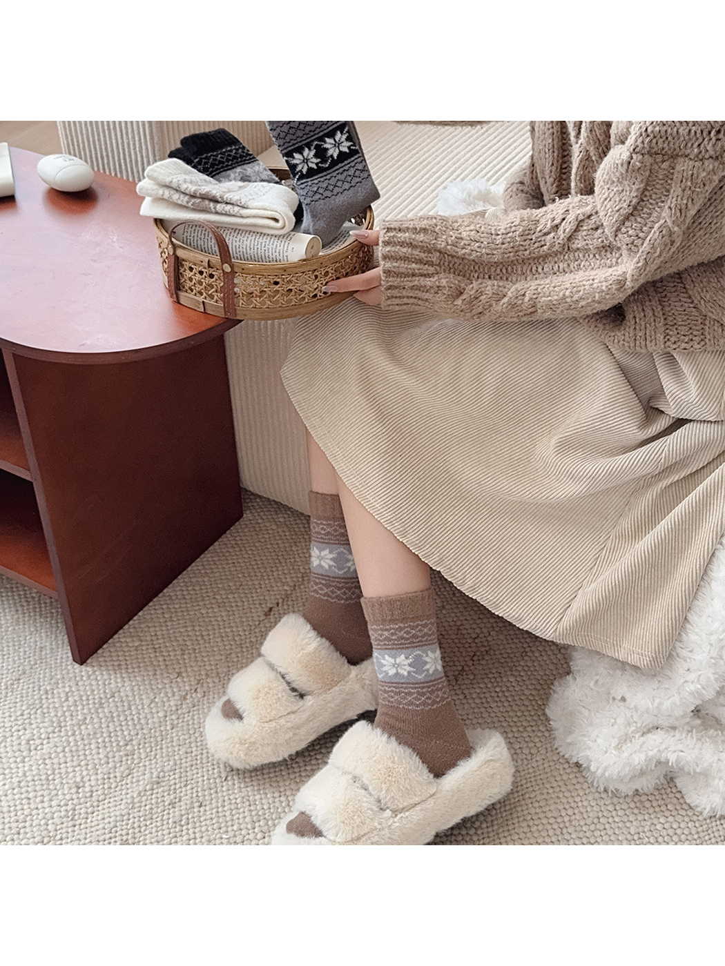 Brown snowflake socks worn with ivory slippers in a seated setting