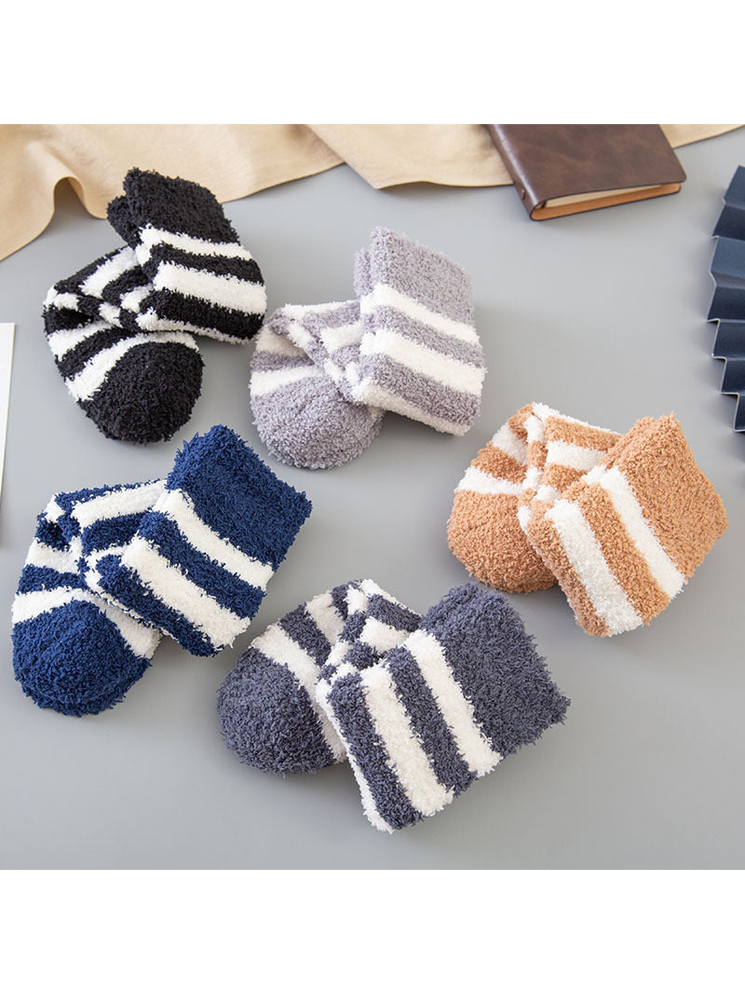 Five colors of striped fuzzy crew socks arranged in rolled pairs