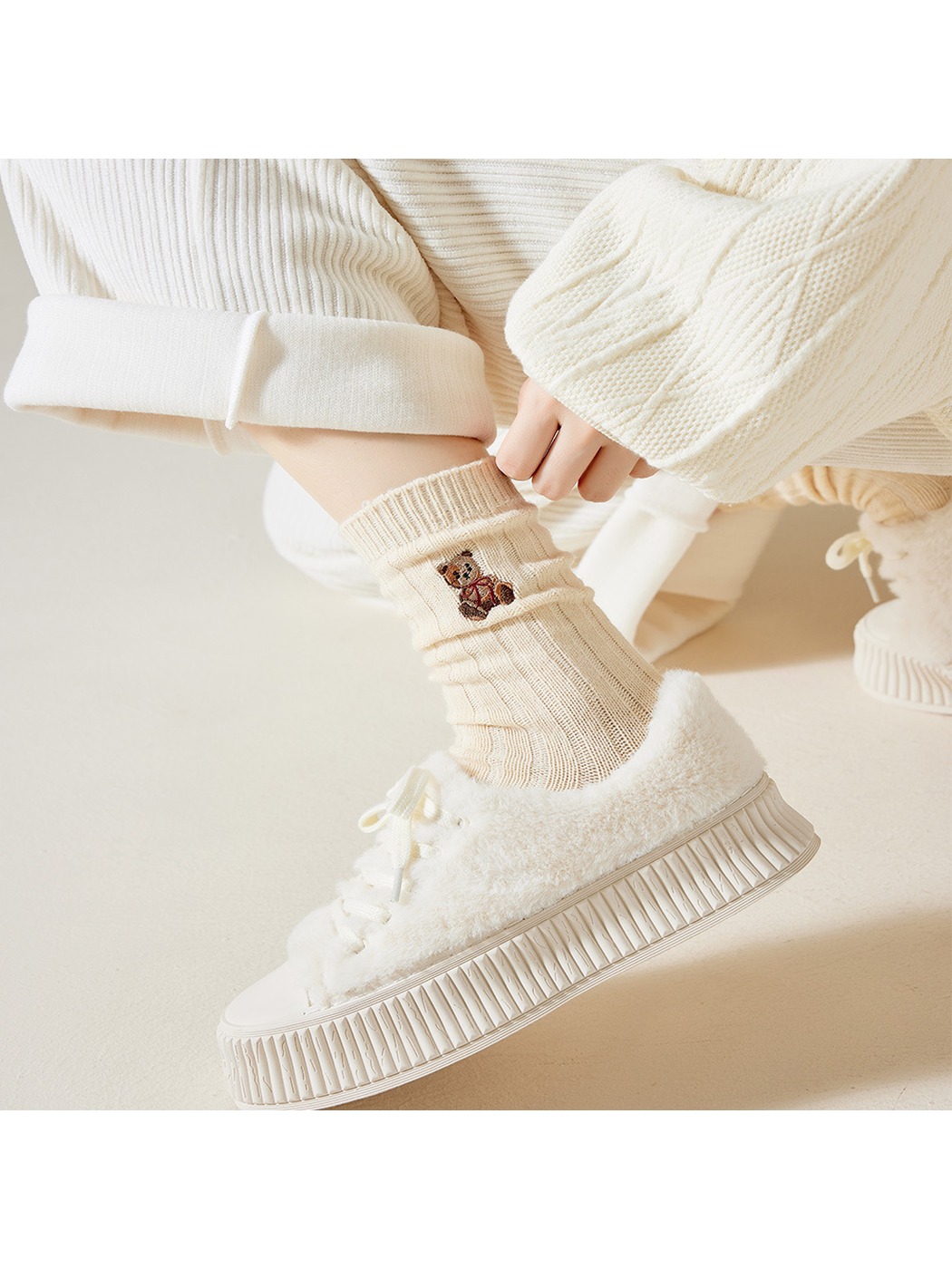 Cream teddy bear crew sock with gathered ribbing above a fuzzy sneaker