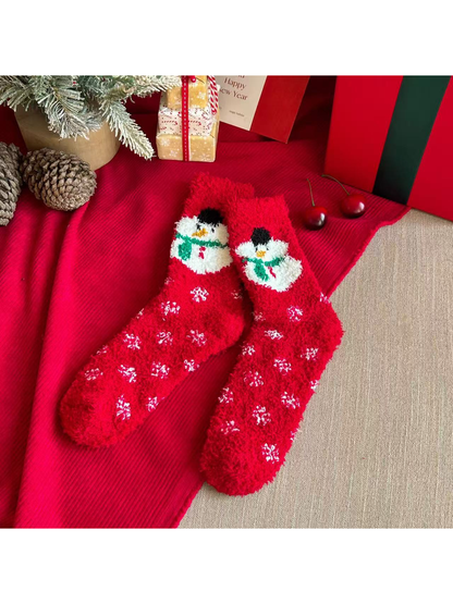 Red fuzzy crew socks with snowman motifs and scattered white snowflakes