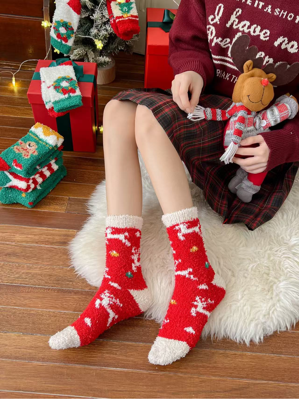 Red reindeer-pattern fuzzy crew socks worn in a festive indoor setting