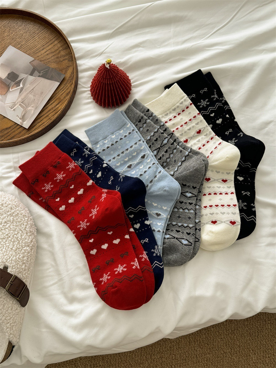Six colors of patterned crew socks arranged together on a white bed