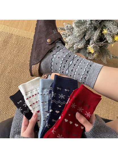 Gray patterned crew socks worn with slippers beside five folded color options
