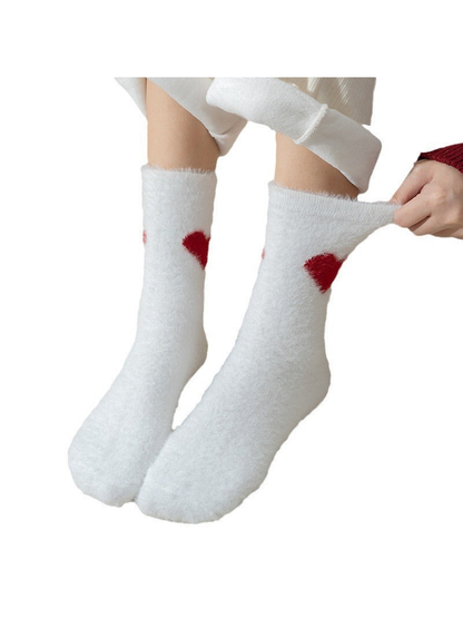 White fuzzy crew socks with red heart motifs shown being stretched