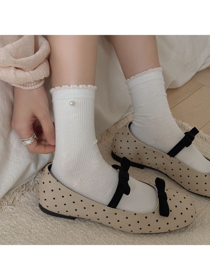 White ribbed crew socks with pearl accents styled with dotted flats