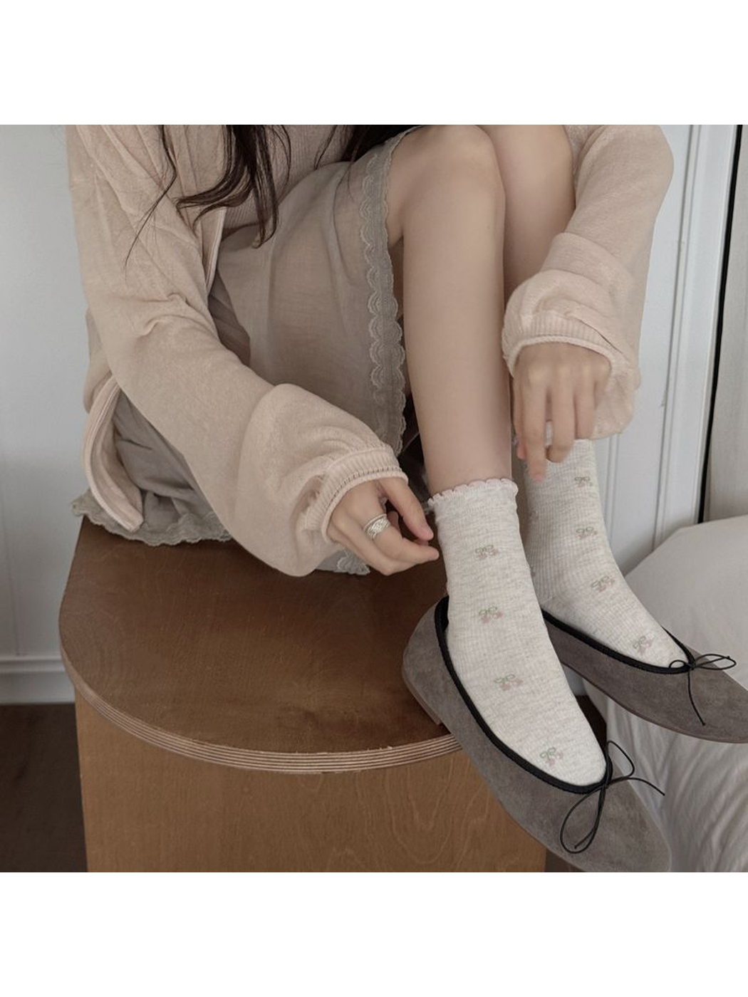Gray cherry-pattern crew socks with pink ruffled cuffs worn with gray flats