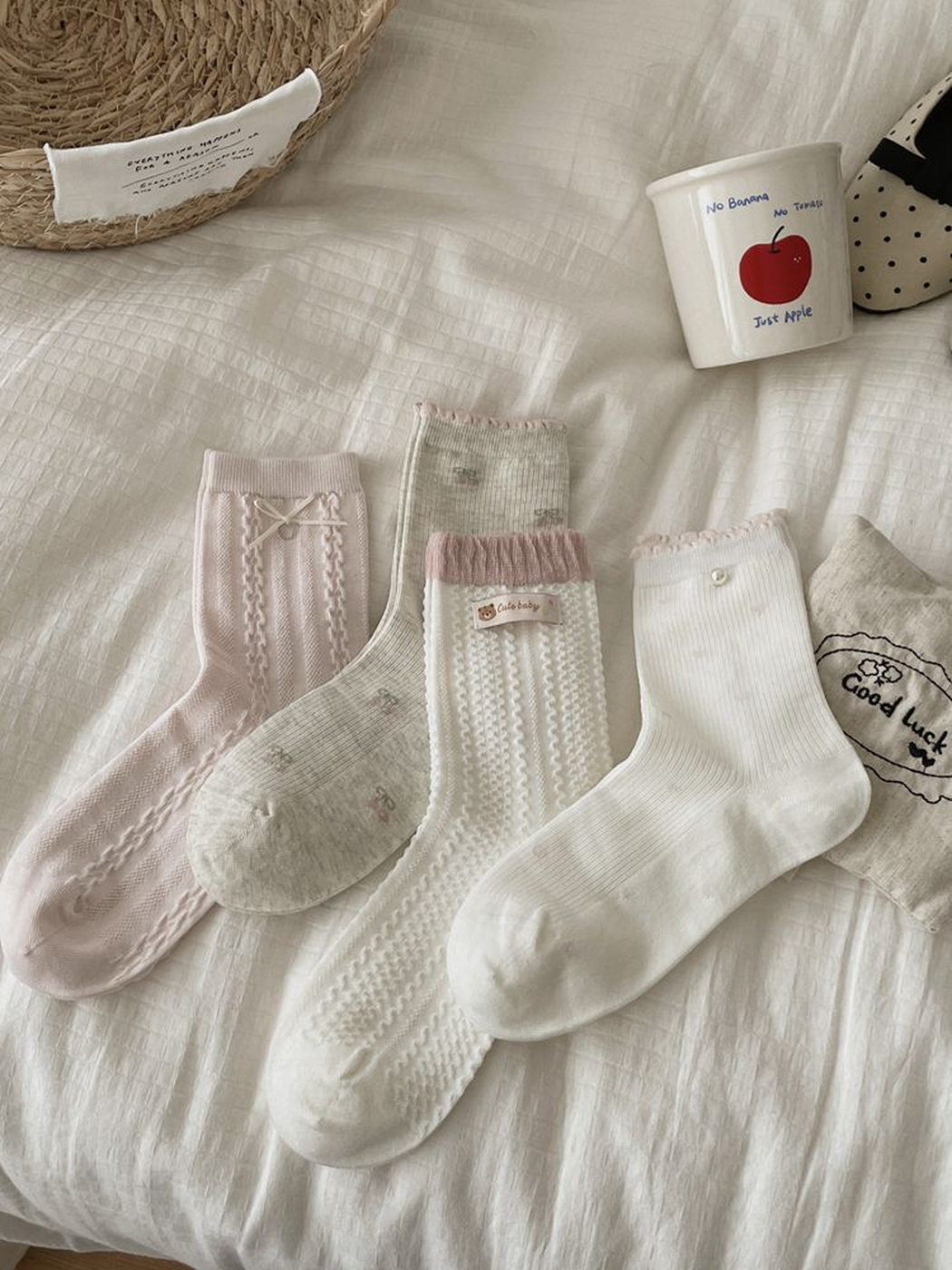 Four pink, gray and white crew sock styles arranged on a cream bedspread