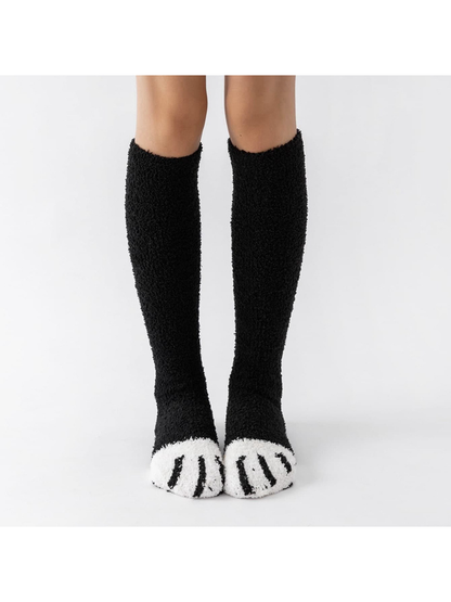 Black fuzzy knee-high socks with contrasting white cat-paw toes, front view